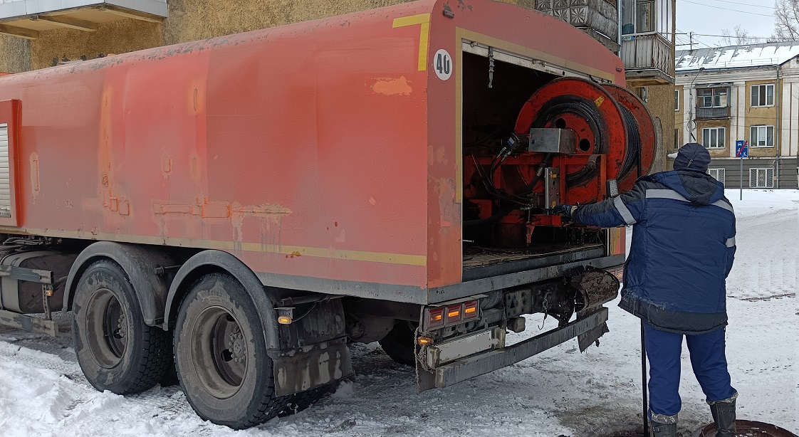 Каналопромывочная машина и работник прочищают засор в канализационной системе в Дно
