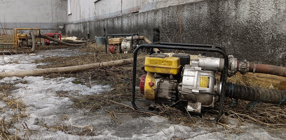 Откачка мотопомпами талой воды из подвала дома в Новоржеве